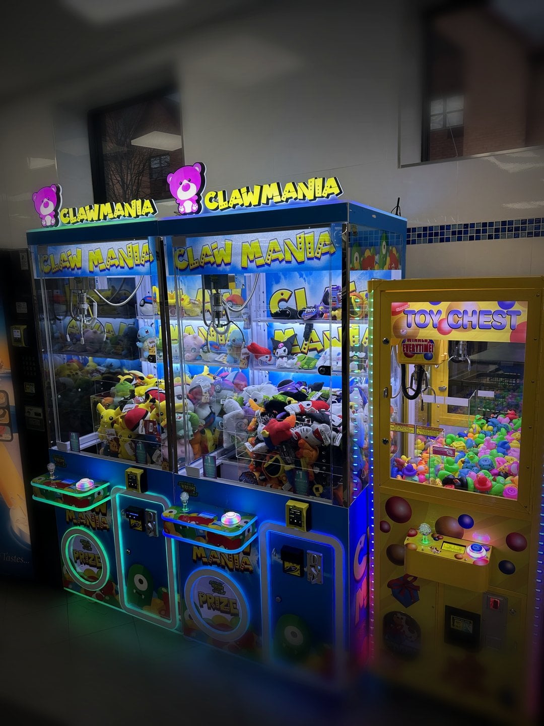 Claw machines by the chairs in a laundromat