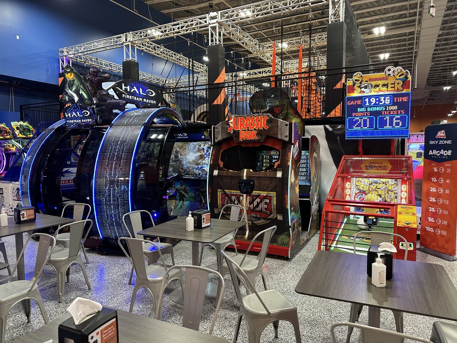 Arcade seating area with Halo, Jurassic Park and Minions Soccer games at a Sky Zone trampoline park, placed by The Arcade Pros