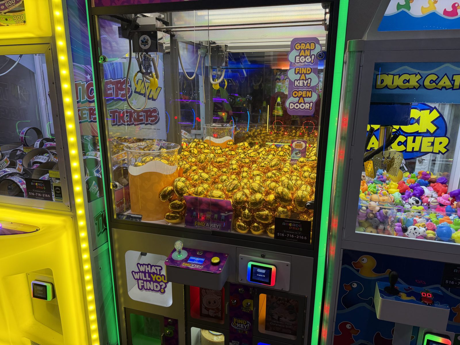 Prize claw machines with Arcade Pros service labels at a Sky Zone trampoline park