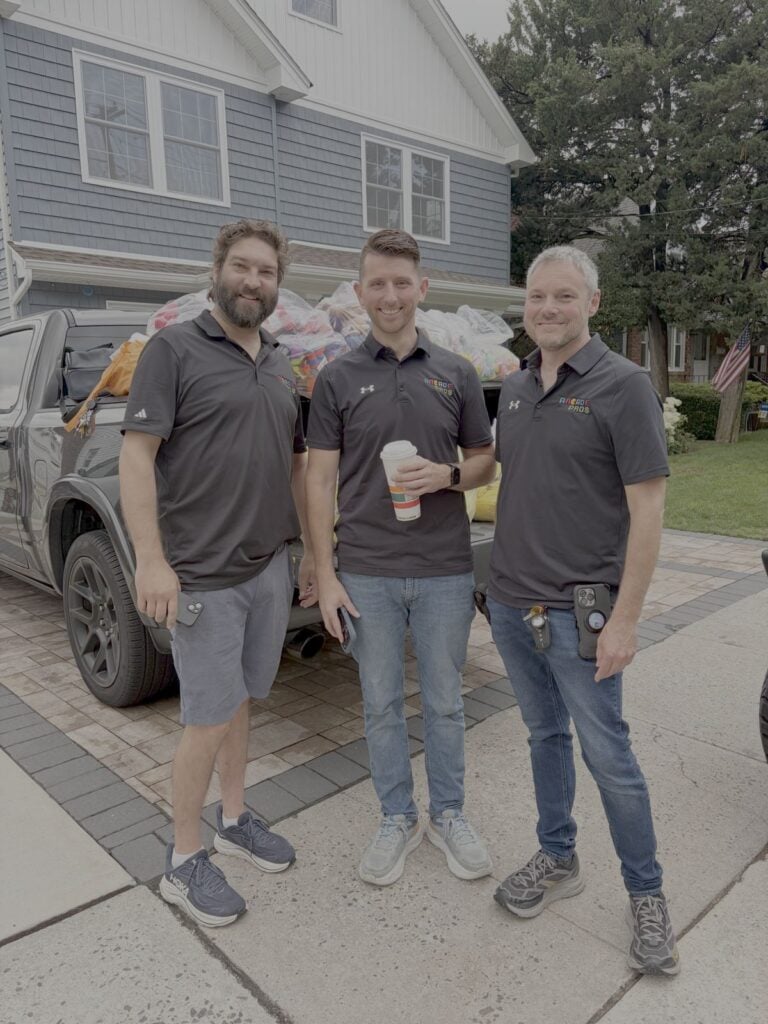 The Arcade Pros team in a driveway next to a truck loaded with prize plush